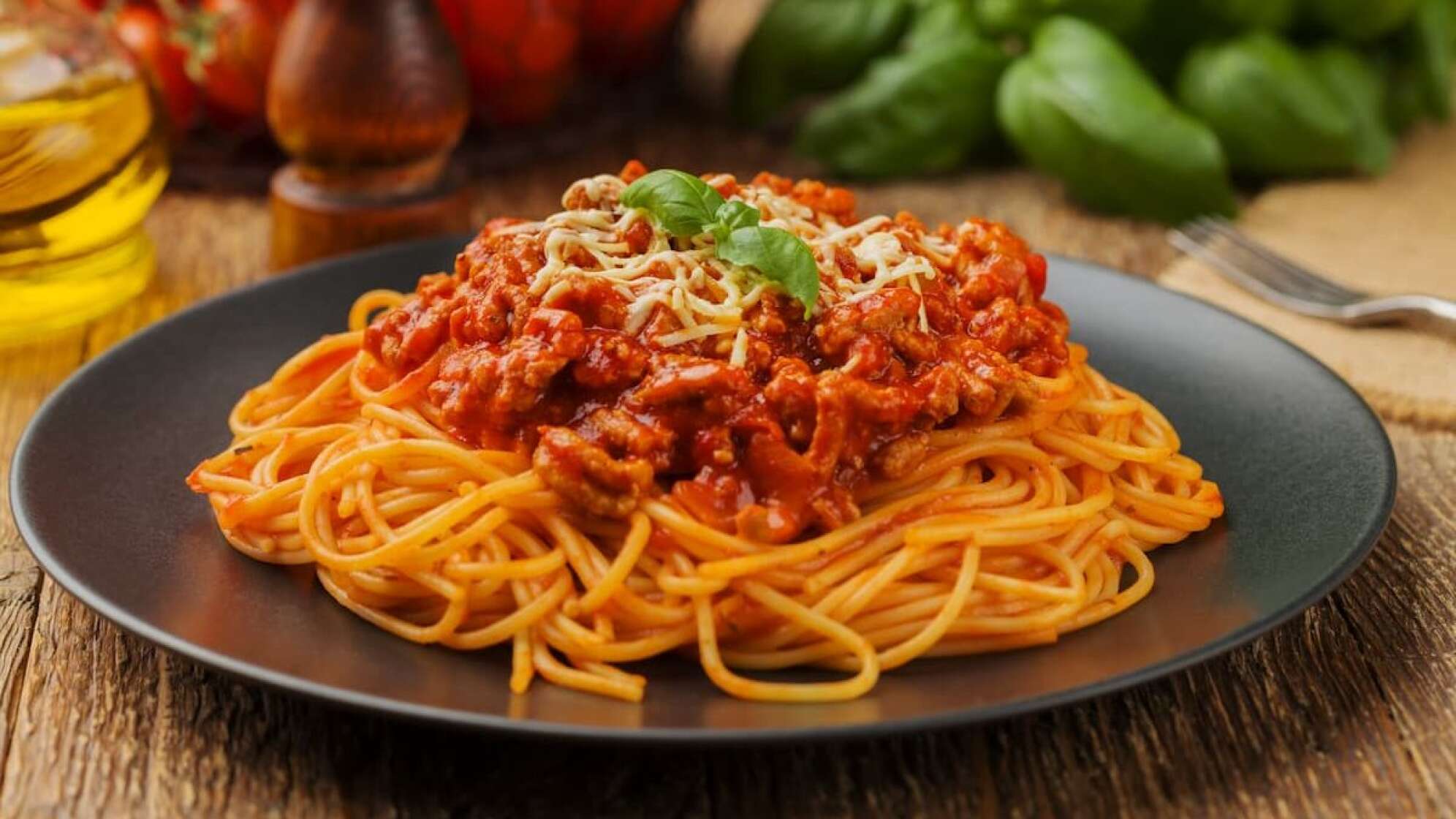 Teller Spaghetti Bolognese mit Zutaten im Hintergrund